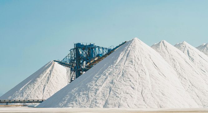 Weiße Berge aus Salz für den Streusalz-Frühbezug vor hellblauem Himmel