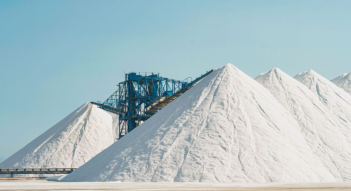 Weiße Berge aus Salz für den Streusalz-Frühbezug vor hellblauem Himmel